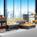 A Rosseto black matte steel chafer alternative warmer on a table with food on display.