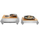 A Rosseto stainless steel chafer alternative warmer base on a table with two plates of food.