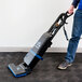 A person using a Lavex HEPA Microfilter upright vacuum cleaner.