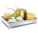 A tray with a white block of cheese and grapes on it in a stainless steel ice housing with a steel tray and acrylic insert.