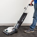 A person using a Lavex upright vacuum cleaner to clean the floor.
