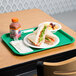A sandwich and fruit on a green plastic fast food tray.