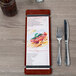A customizable mahogany wood Menu Solutions menu board on a table in an Italian restaurant.