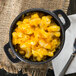 A bowl of macaroni and cheese in a Libbey mini cast iron pot with a fork.