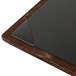 A brown walnut wood menu board with black picture corners on a table in a bar.