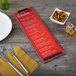 A customizable wood Menu Solutions clip board on a table with a menu, fork, and knife.