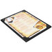 A black Menu Solutions wood menu board with picture corners on a table.