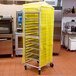 A yellow Curtron Supro mesh cover on a metal bun pan rack.
