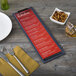 A Menu Solutions wood menu clip board on a table with a menu and utensils.