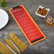 A Menu Solutions wood clip board on a table with a menu, fork, and knife.