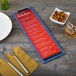 A customizable wood menu clip board on a table with a menu and a bowl of nuts.