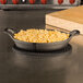 A pan of macaroni and cheese in an American Metalcraft Mini Cast Iron Oval Casserole Dish on a table.