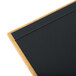 A Menu Solutions oak wood menu board with black strips on a table with a black marker.