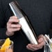 A person holding a Barfly stainless steel Boston cocktail shaker.