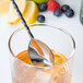 A Barfly stainless steel Japanese bar spoon in a glass of liquid with berries.