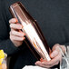 A person holding a copper Barfly cocktail shaker.
