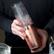 A man using a Barfly copper cocktail shaker tin to make a drink with ice.