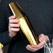 A person holding a Barfly gold-plated cocktail shaker.