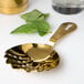 A gold Barfly scalloped julep strainer with a leaf.