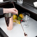A person using a Barfly copper plated Japanese style bar spoon in a metal cup next to a glass and fruit.
