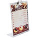 An Alumitique aluminum menu tent clip with a swirl finish holding a menu on a table.
