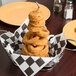 A stack of fried onion rings in an American Metalcraft oval basket.