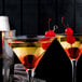 Two glasses of martinis with cherries on stainless steel cocktail picks.
