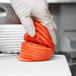 A person in gloves using a Vollrath Tomato Pro slicer to slice a tomato.