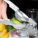 A hand using a Barfly citrus squeezer to juice a lime.