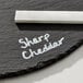 A round black slate tray with a piece of white soapstone chalk resting on it.