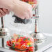 A hand using a Choice Triple Canister Cereal Dispenser to fill a plastic bag with candy.