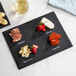 A rectangular black slate tray with labeled sections for food, accompanied by soapstone chalk.