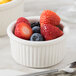 A close-up of a white Tuxton fluted ramekin filled with strawberries.