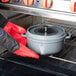 A person wearing red gloves holding a grey GET Heiss cast aluminum dutch oven with lid in an oven.