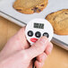 A person holding a Cooper-Atkins digital kitchen timer with a cookie in the background.