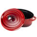 A red oval Dutch oven with a black lid with a red knob.