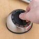 A hand turning the dial on a Cooper-Atkins kitchen timer on a kitchen counter.