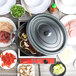 A black GET Heiss oval dutch oven with a lid on a table with food and meat.