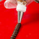 A person using an Ateco Lily-of-the-Valley piping tip to pipe chocolate onto a spiral.