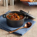 A Valor pre-seasoned cast iron pot filled with soup with a lid and a spoon.