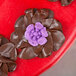 A chocolate flower piped with a Ateco 246 Russian Piping Tip with purple frosting.