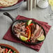 A Valor pre-seasoned cast iron fajita skillet with steak, peppers, and onions on a table.