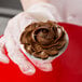A person holding a chocolate cupcake with a rose made of chocolate frosting on top using an Ateco stainless steel flower nail.