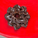 A chocolate swirl piped with an Ateco Russian ball tip on a red surface.