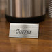 A silver metal Cal-Mil coffee beverage tent on a table next to a coffee maker.