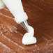 A pastry bag with a Ateco ruffle piping tip on a brown surface.