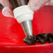 A person using an Ateco swirl top piping tip to decorate a cake.