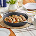 A Valor cast iron skillet with sausages and vegetables on a table.