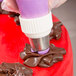 A person using an Ateco Russian piping tip to decorate chocolate frosting on a cake.