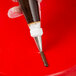 A hand holding an Ateco square tip on a pastry bag with brown frosting.